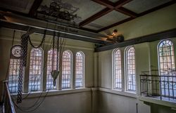 Historische Krananlage mit Kettenzug im Schaukraftwerk Schwellöd vor hohen Rundbogenfenstern der ehemaligen Maschinenhalle.