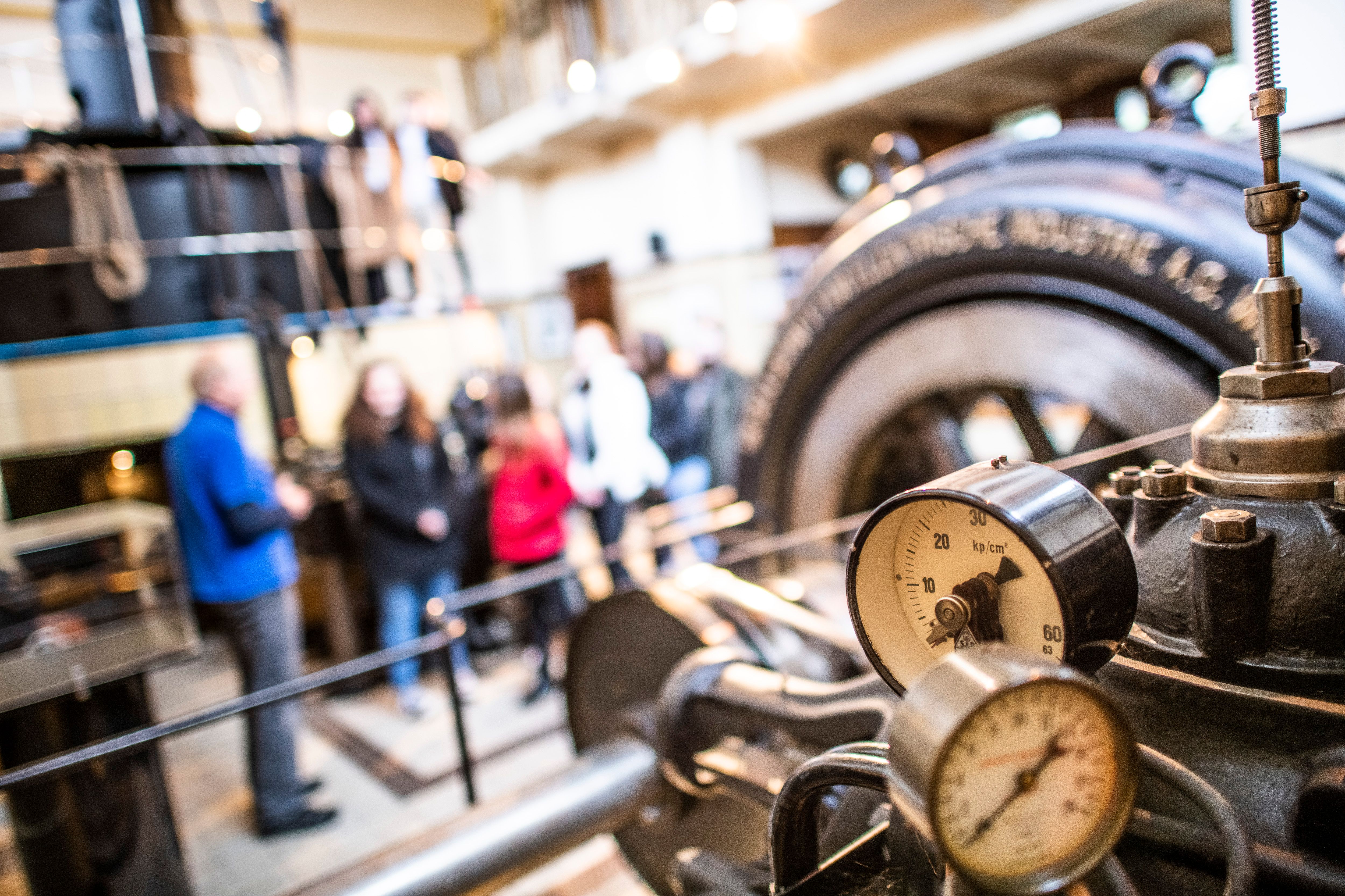 Manometer und historische Maschinentechnik im Schaukraftwerk Schwellöd, während Besucher an einer Führung durch das denkmalgeschützte Wasserkraftwerk teilnehmen.